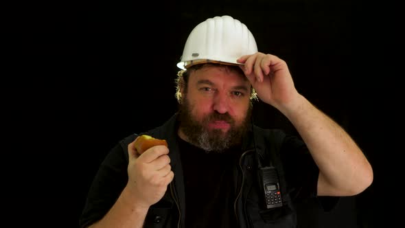 Concept idea: Funny bearded foreman with helmet takes a break and eats a healthy apple