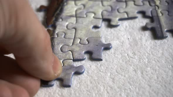 Man places small pieces of a puzzle, close up shot 4K alt