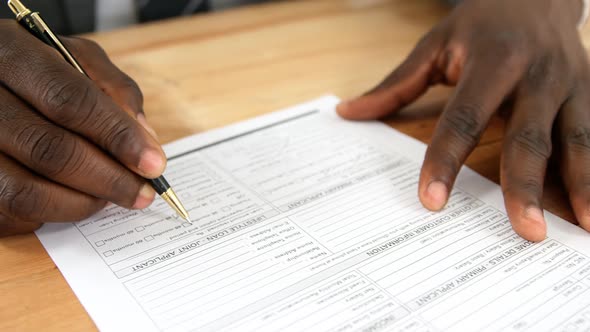 Agent sitting at desk filling mortgage contract form alt