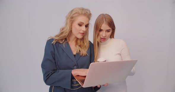 Two Girls Look At The Laptop And Communicate