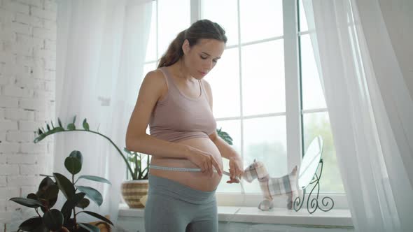Pregnant Woman Measuring Belly with Tape. Belly Mother Surprising Tummy Volume. alt