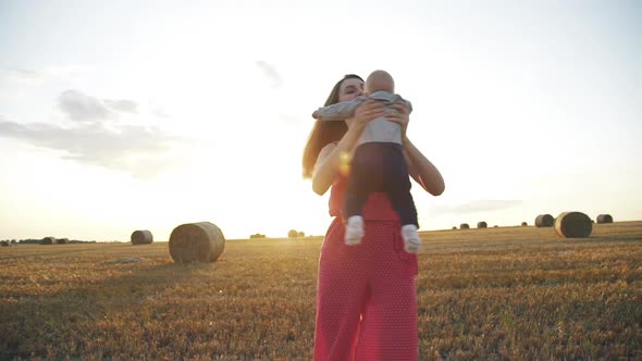 Mother Whirling Kissing and Throwing Her Baby Son in a Field Near Haystacks alt