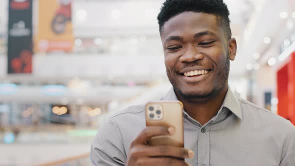 Happy Smiling Guy Walks Indoors Reads Good Email Message on Phone Uses Free Wifi Chatting in Social alt