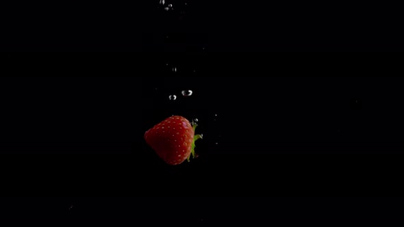 Strawberry Falling into Water Super Slowmotion, Black Background, lots of Air Bubbles, 4k240fps alt