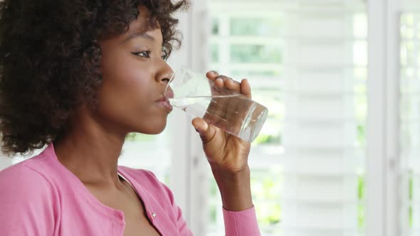 Woman drinking glass of water and smiling alt
