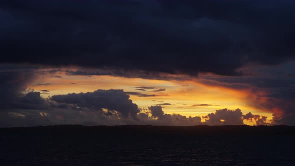Panoramic View of Orange Skies with Puffy Clouds with the Calm Sea Beneath It alt