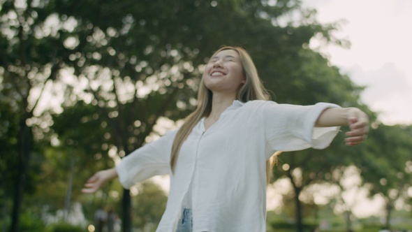 A beautiful Asian woman spun and closed her eyes enjoying the breeze.