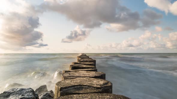 Sea Waves around the wooden pier, Clouds, and Blue Sky