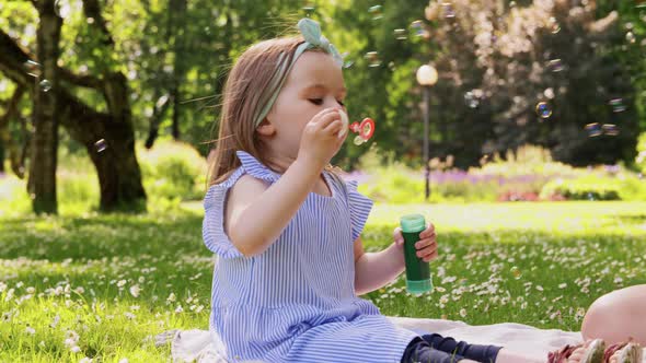 Little Girl Blowing Soap Bubbles at Park or Garden