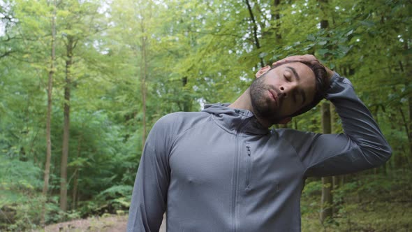 Athlete In Grey Stretching Neck Muscles In Forest