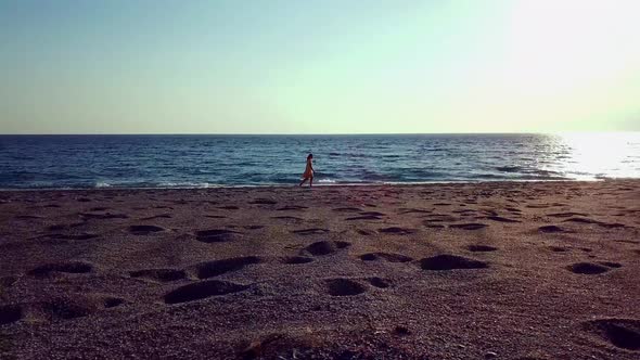 Aerial Drone Footage of a Girl Walking Along a Lonely Beach