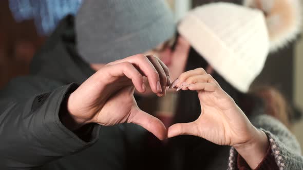 Couple Making Heart Shape with Hands Standing in Night City alt