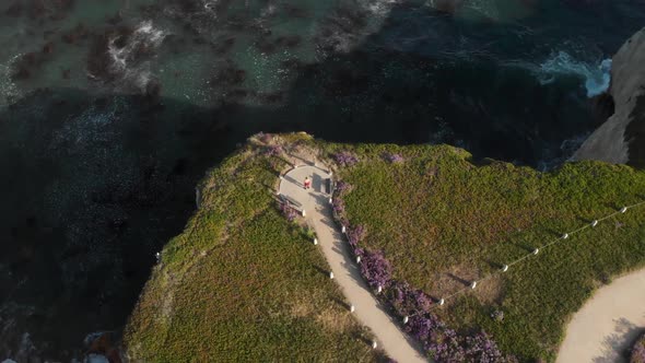 Drone Circles Around Person Standing on Cliffs Looking out Towards Ocean