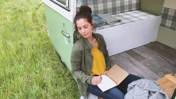 Slow motion shot of woman sitting in camper and writing in daybook