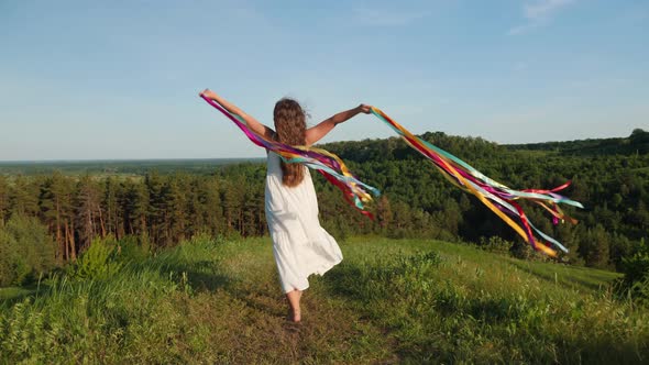 Girl with Rainbow Ribbons in Hands Walks in Nature
