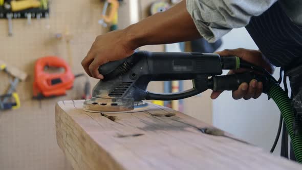 Carpenter polishing wood with machine 4k alt