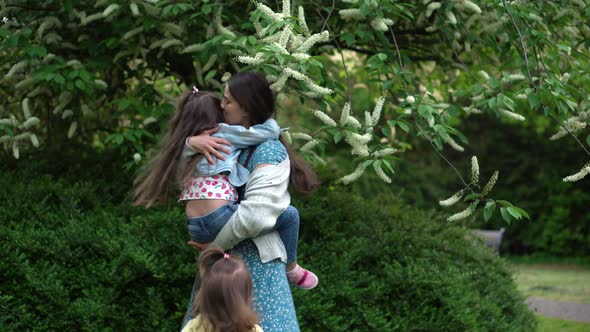 Happy Family Mother with Two Daughter Little Kid Have Fun Sniffing Flowers on Trees Enjoying Summer
