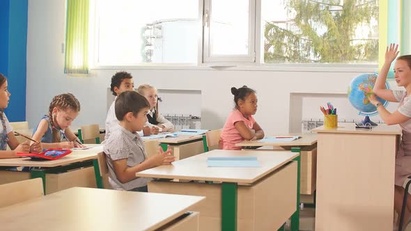 Group of School Children All Raising Their Hands in the Air To Answer alt
