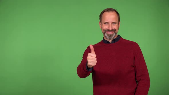 A Middleaged Handsome Caucasian Man Shows a Thumb Up to the Camera with a Smile  Green Screen