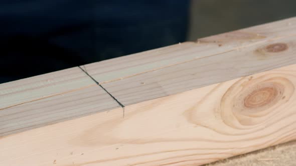 Worker Makes Mark on Beam with Pencil and Cuts Wood with Milling Machine alt