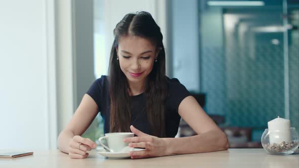 Dreamy Young Woman Holding a Cup of Coffee and Singing at the Cafe alt