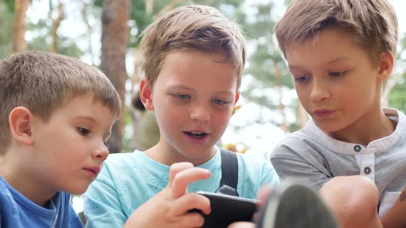 Children Looking at Phone Screen, Children Playing Video Game Outdoor, Three European Kids Follow