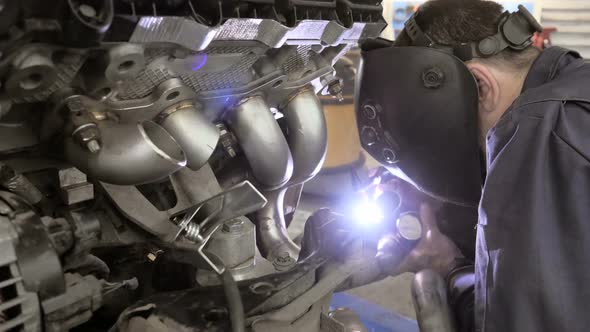 A Man In Helmet Doing Argon Welding Parts. Welder Welding A Metal Parts On Vehicle alt