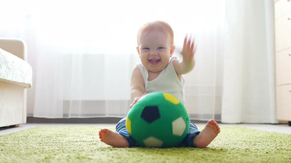 Readhead Baby Girl Playing with a Soccer Ball on the Floor in Sunny Room
