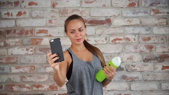 Cute Woman Taking Photos on Phone Lady Holding Small Bottle of Water in Her Hand alt