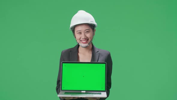 Asian Female Engineer With Safety Helmet Showing Green Screen Laptop In The Green Screen Studio alt