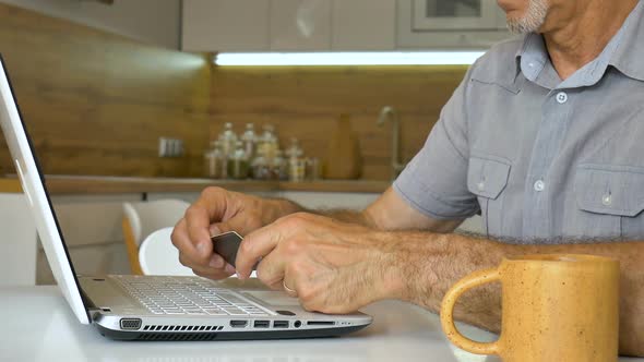 Senior Man is Typing on Keyboard of Laptop Businessman is Using Digital Tablet at Home at the alt