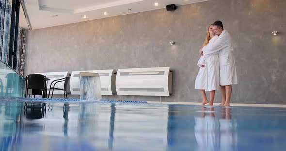 Man in White Robe Approaches Young Woman and Hugs By Pool