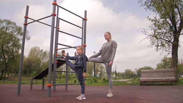  Mother and Daughter Doing Exercises on Open Air Sport Playground
