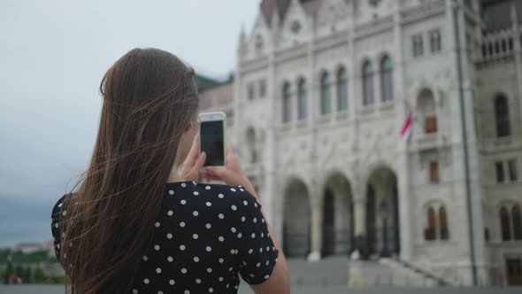 Girl Taking Mobile Photos of Parliament Building in Budapest Hungary alt