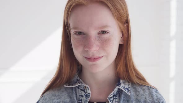 Funny Redhead Teenage Girl with Freckles Against White Wall with Sun Rays alt