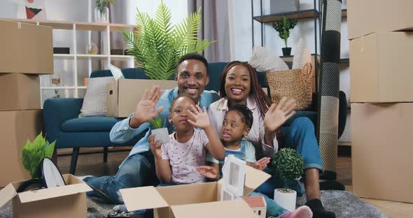African American Family with Two Small Kids Sitting on the Floor in Newly Acquired Apartment  alt