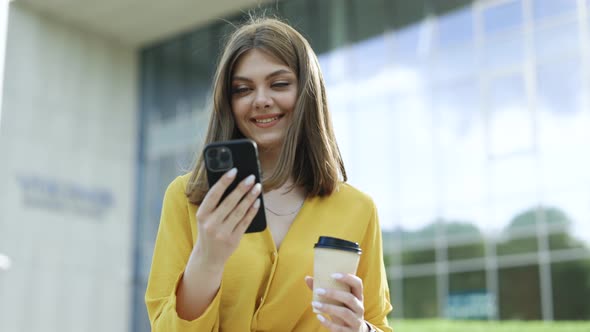 Joyful Young Attractive European Business Girl Using Mobile Phone Drinking Coffee Spending Time alt