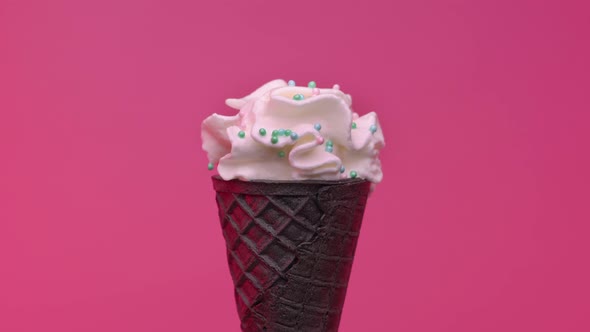 Soft ice cream in black cone decorated with colorful sprinkles