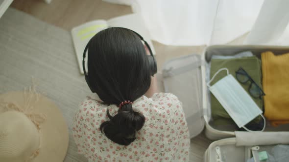 Travel Asian girl lying on the floor in the bedroom reading book and listening to music. alt