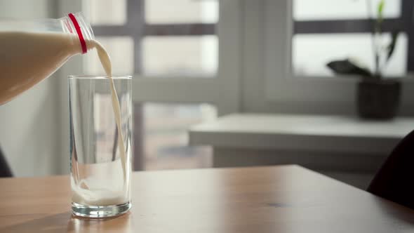 Closeup of a Female Hand Pouring Milk From a Bottle Into a Glass Indoors Cinematic Shot
