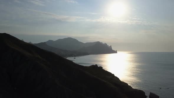 Flight Over the Sea and Mountains at Sunrise. Aerial View of Kara-Dag Mountain in Crimea. alt
