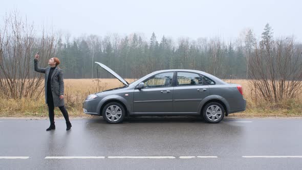 Young Woman Searching for a Mobile Network with a Broken Car. alt