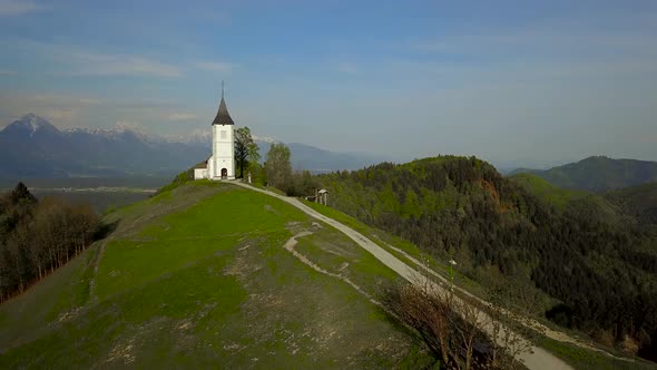 drone footage sunset at Church of St. Primus and Felician, Jamnik, Slovenia  alt