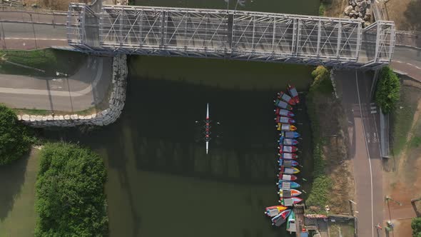 Four seat rowing canoe crossing under a bridge, heading downstream. alt