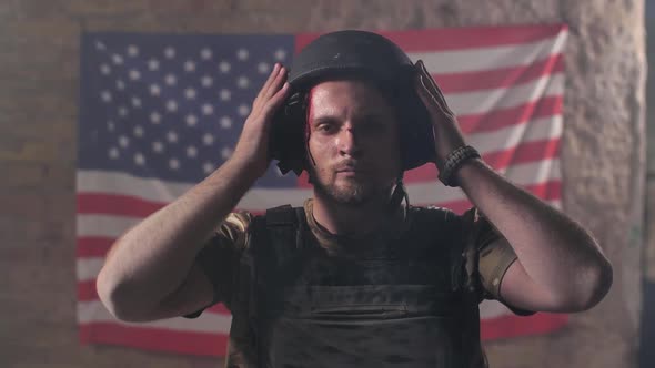 Proud Injured Soldier in Helmet Against US Flag alt