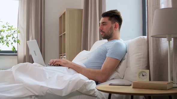 Man with Laptop in Bed at Home Bedroom