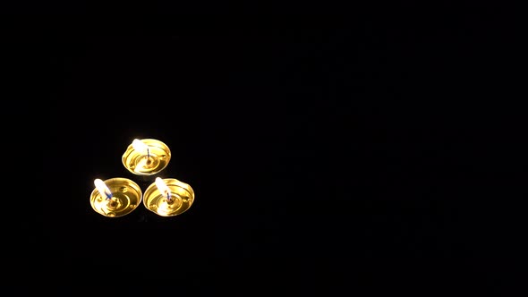 three candles on a black background with a fireplace flame.