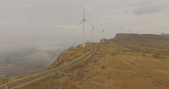 An electric motorcycle riding against the backdrop of windmills churning green renewable energy alt