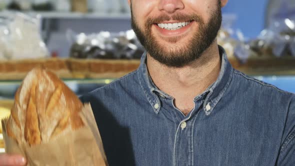 Cropped Close Up f a Bearded Man Smiling Holding a Loaf of Fresh Bread