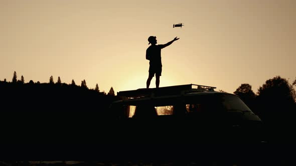Silhouette A Man Lands a Drone Landing on His Hand in Nature at Sunset